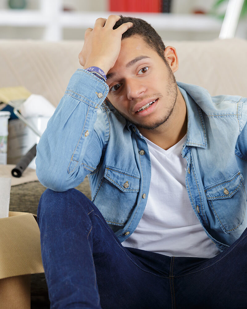 A young man sitting among moving boxes, upset about a conflict with his landlord.