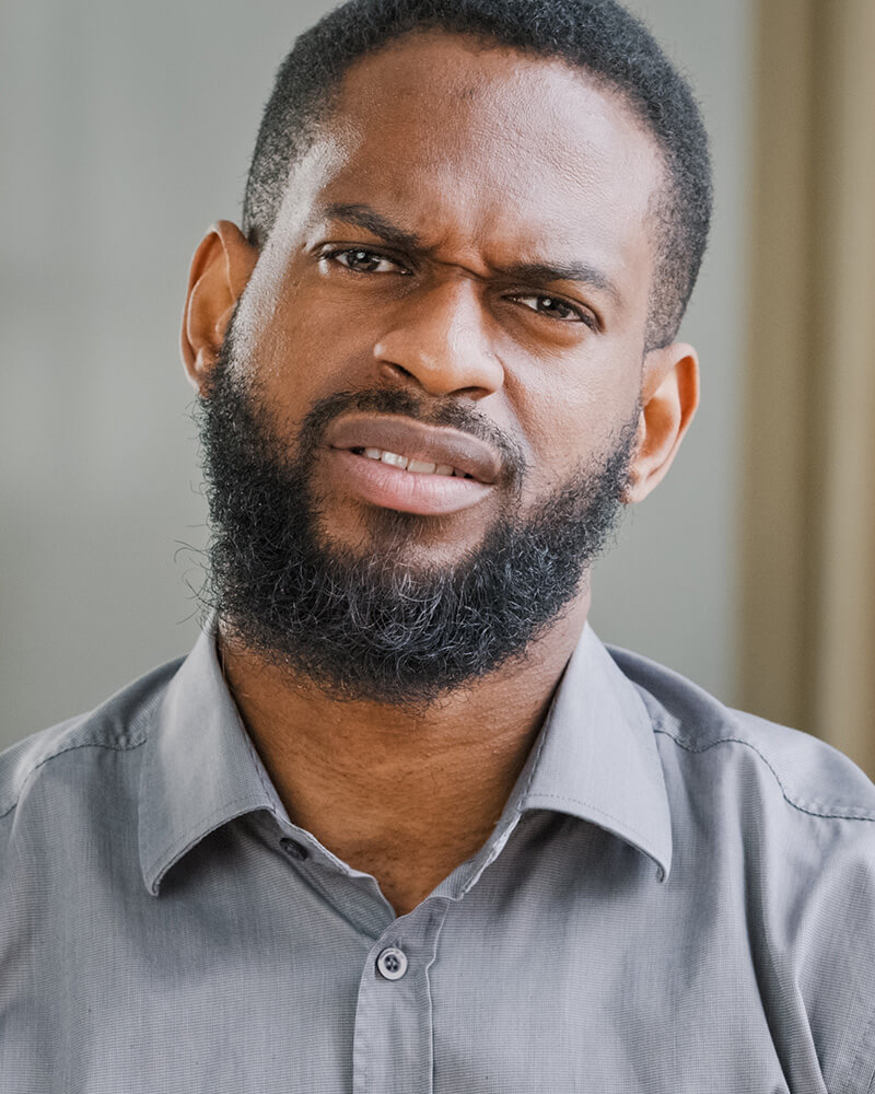 A man looking directly at the camera with a frustrated, questioning expression after being treated unfairly.